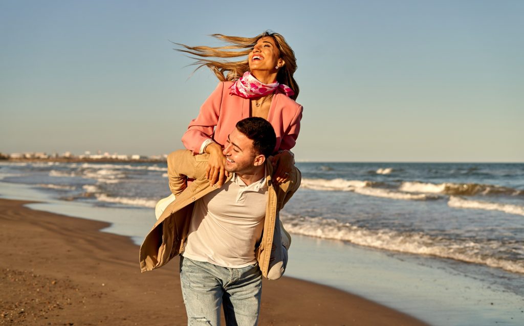 Young couple having fun at the beach in sunset